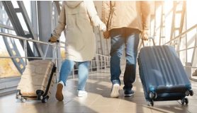 black couple with luggage walking 