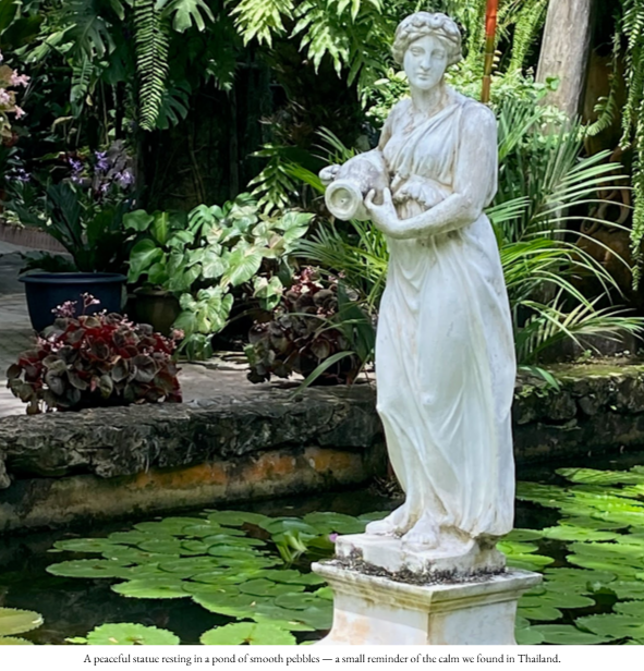 Statue resting in a pond of pebbles in Thailand.